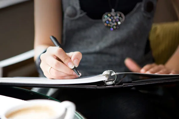 Woman writing in a binder with a pen